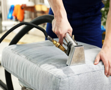 Dry cleaner's employee removing dirt from furniture in flat, clo